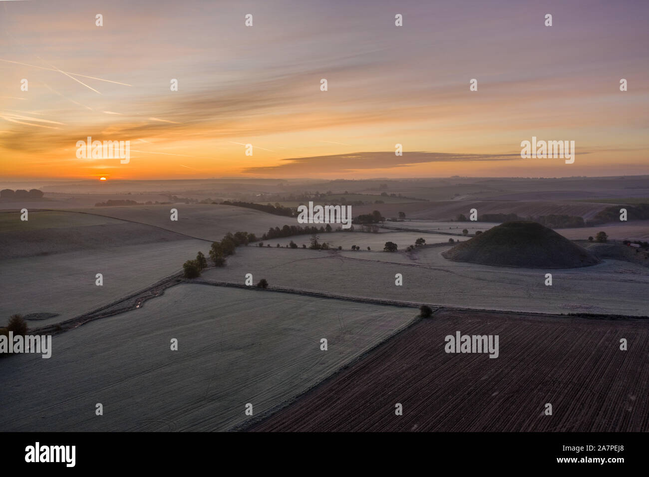 Silbury Hill, Nr Avebury, Wiltshire, UK. 28th October 2019. Drone image of a frosty red morning sky above the ancient man-made mound of Silbury Hill. Stock Photo