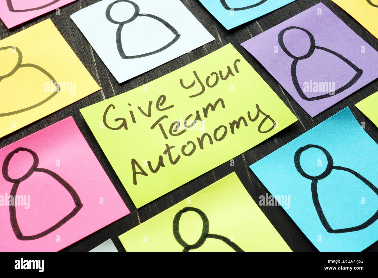 Give Your Team Autonomy sign and drawn smiles faces. Stock Photo