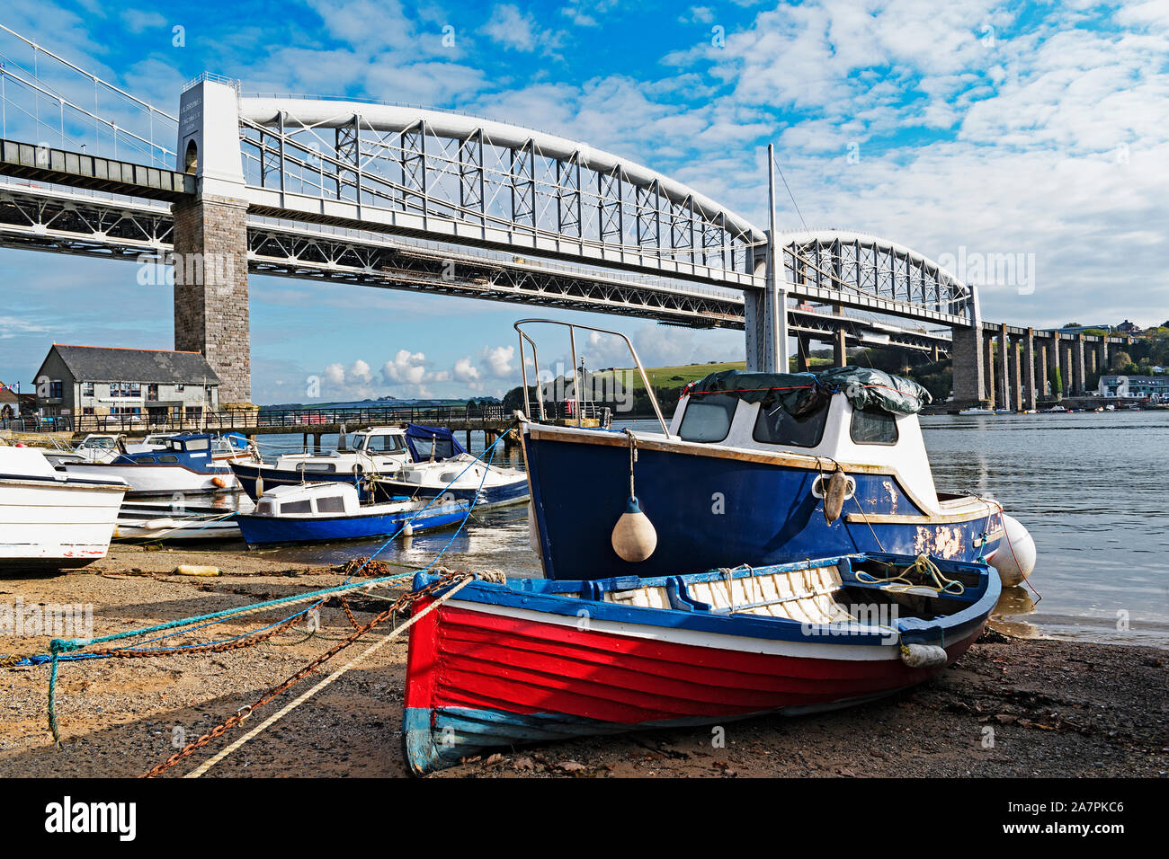 fishing boats by the river tamar in saltash cornwall, the famous royal albert bridge designed by isambard kingdom brunel in the background Stock Photo