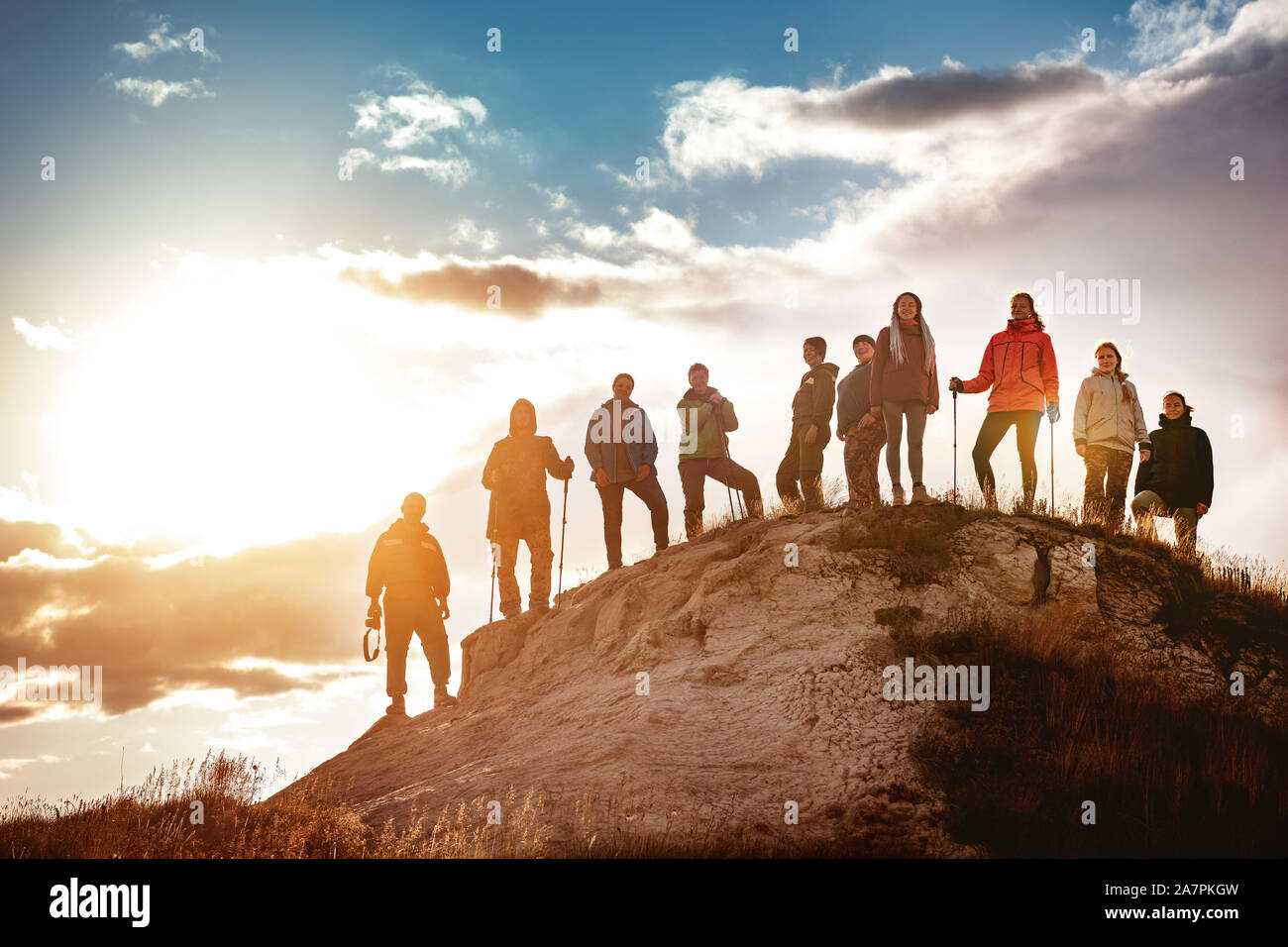 Big group of hikers stands against sunset. Hiking or trekking concept Stock Photo