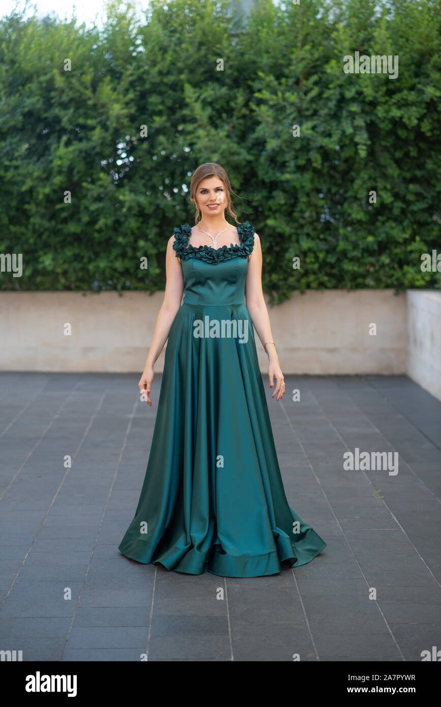 Happy woman dancing in evening gown outdoors Stock Photo