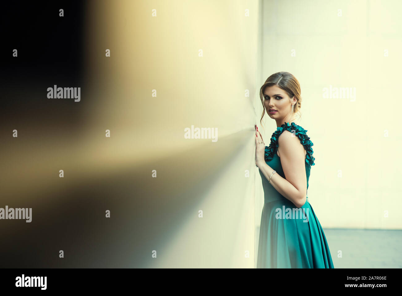 Beautiful woman leaning against wall outdoors looking at camera Stock Photo