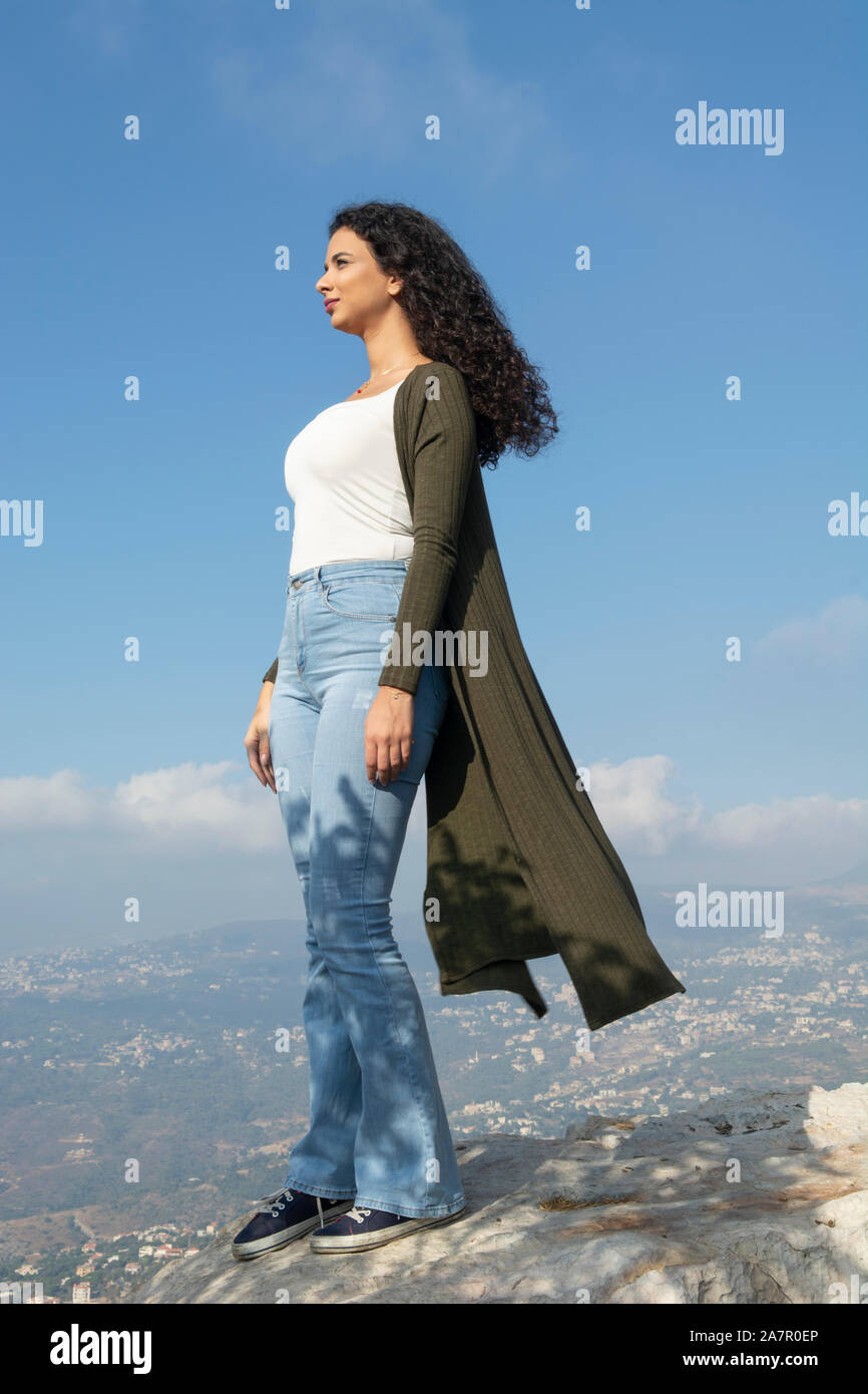 Beautiful young woman standing on top of mountain Stock Photo