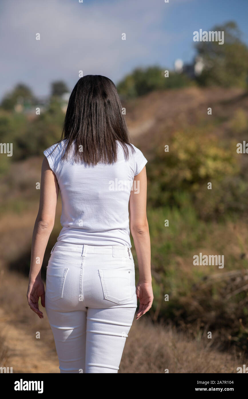 Rear view of young woman walking away in the field Stock Photo - Alamy
