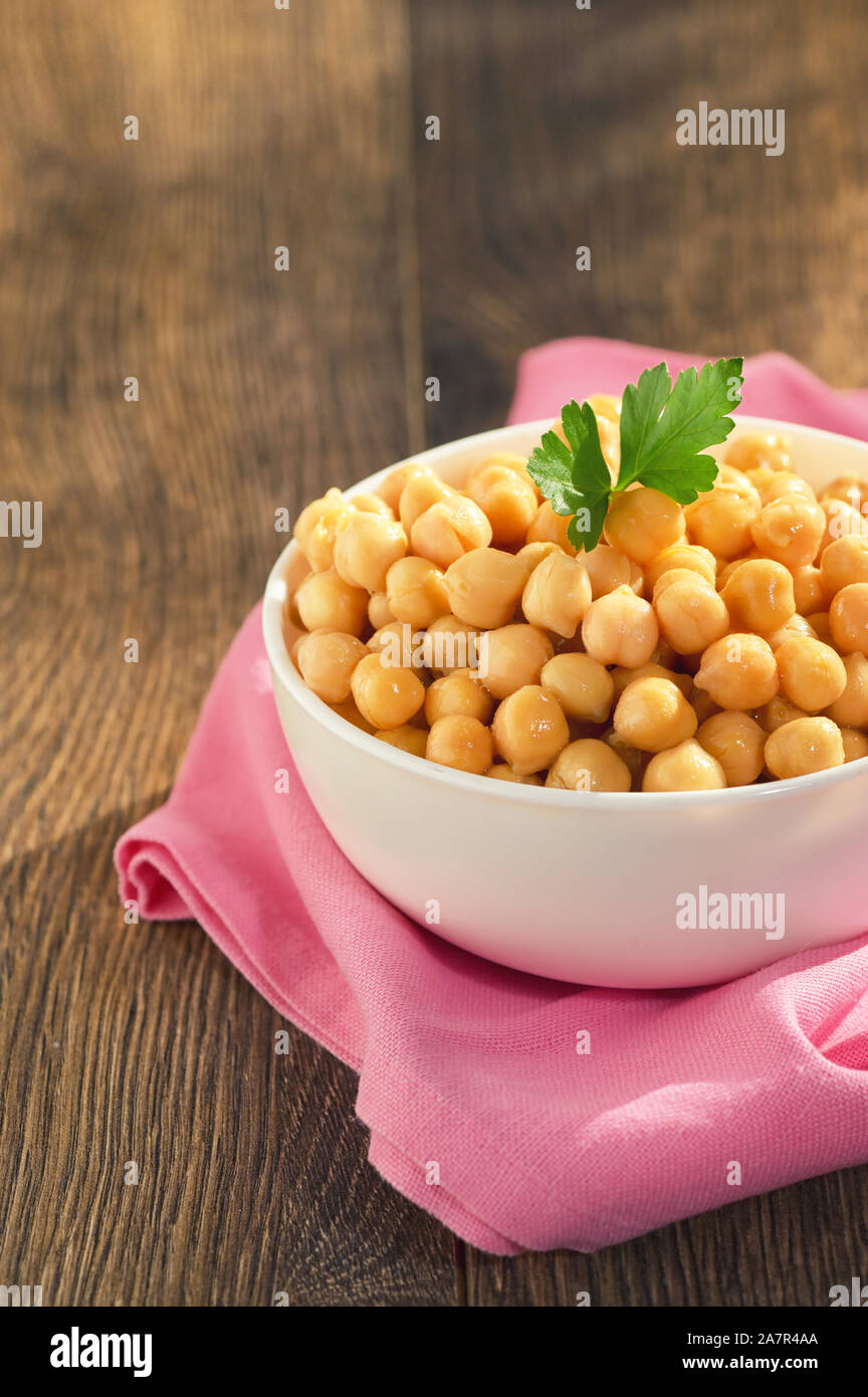 Cooked Chickpeas In Ceramic Bowl on wooden table Stock Photo
