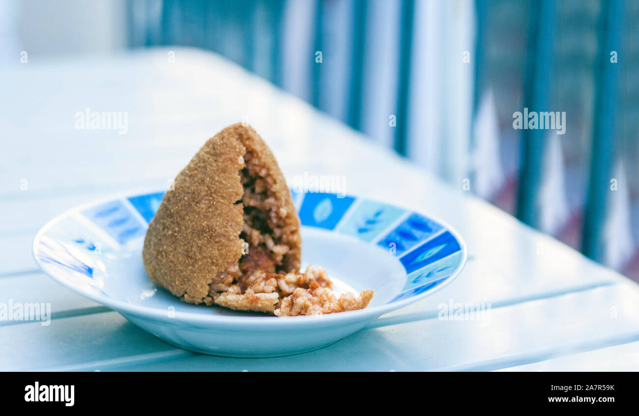 Sicilian snack, fried ball of rice “arancino” on a plate, tipical street food of Sicily Stock Photo
