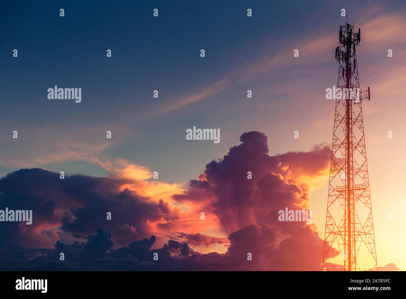 Dramatic dusk sky colorful cloud with communication signal tower silhouette. Stock Photo