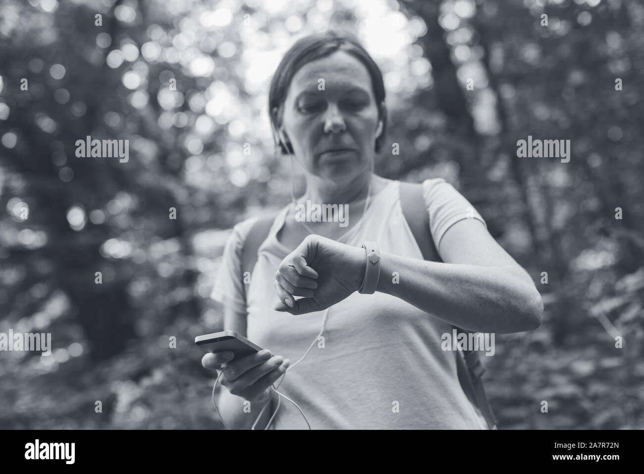 Female hiker checking fitness tracker wristband data and synchronizing