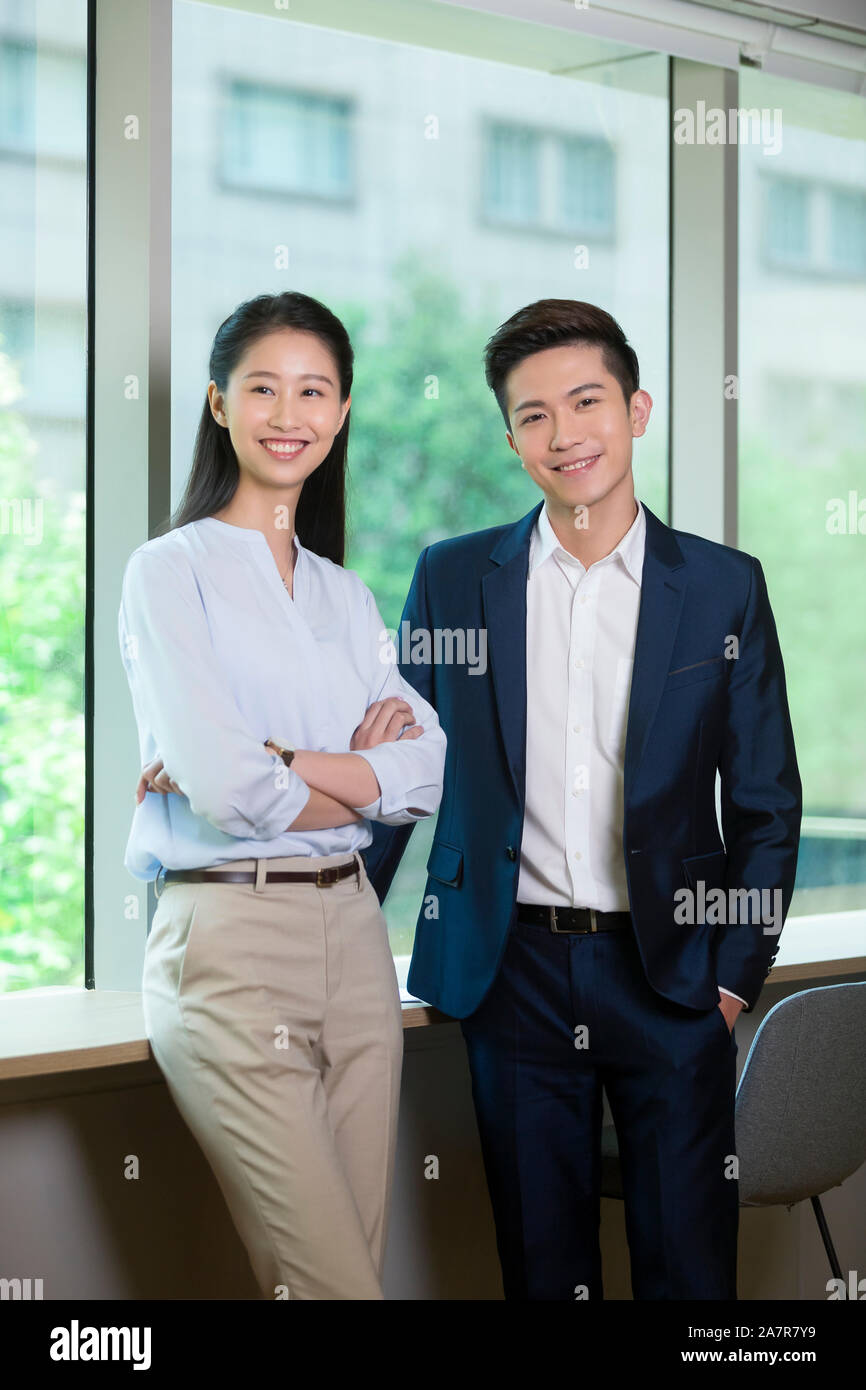 Three quarter length portrait of two smiling young male and female businesspeople standing while wearing businesswear and looking at the camera Stock Photo