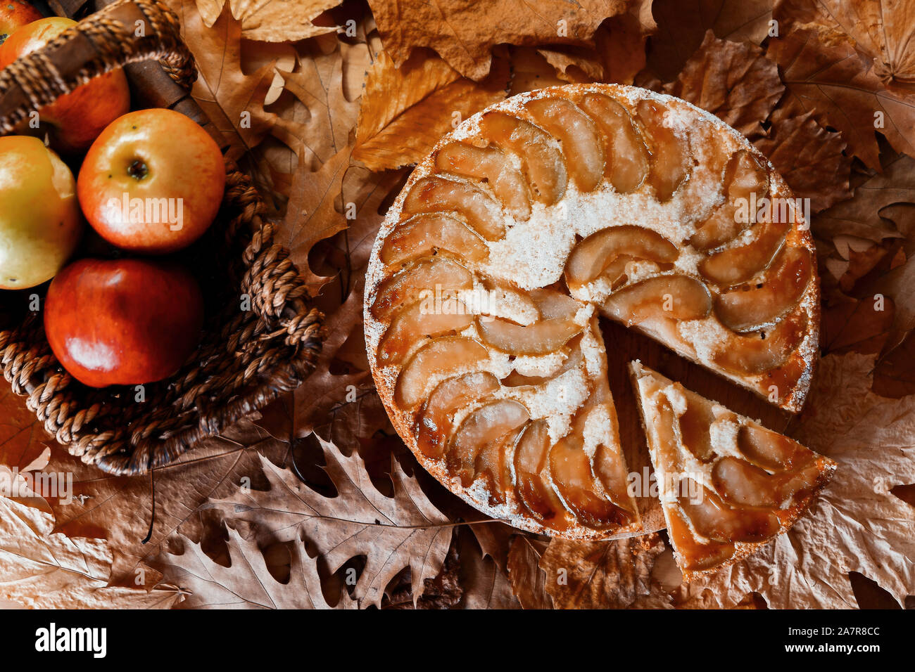 Freshly baked homemade apple pie near red apples in straw basket on