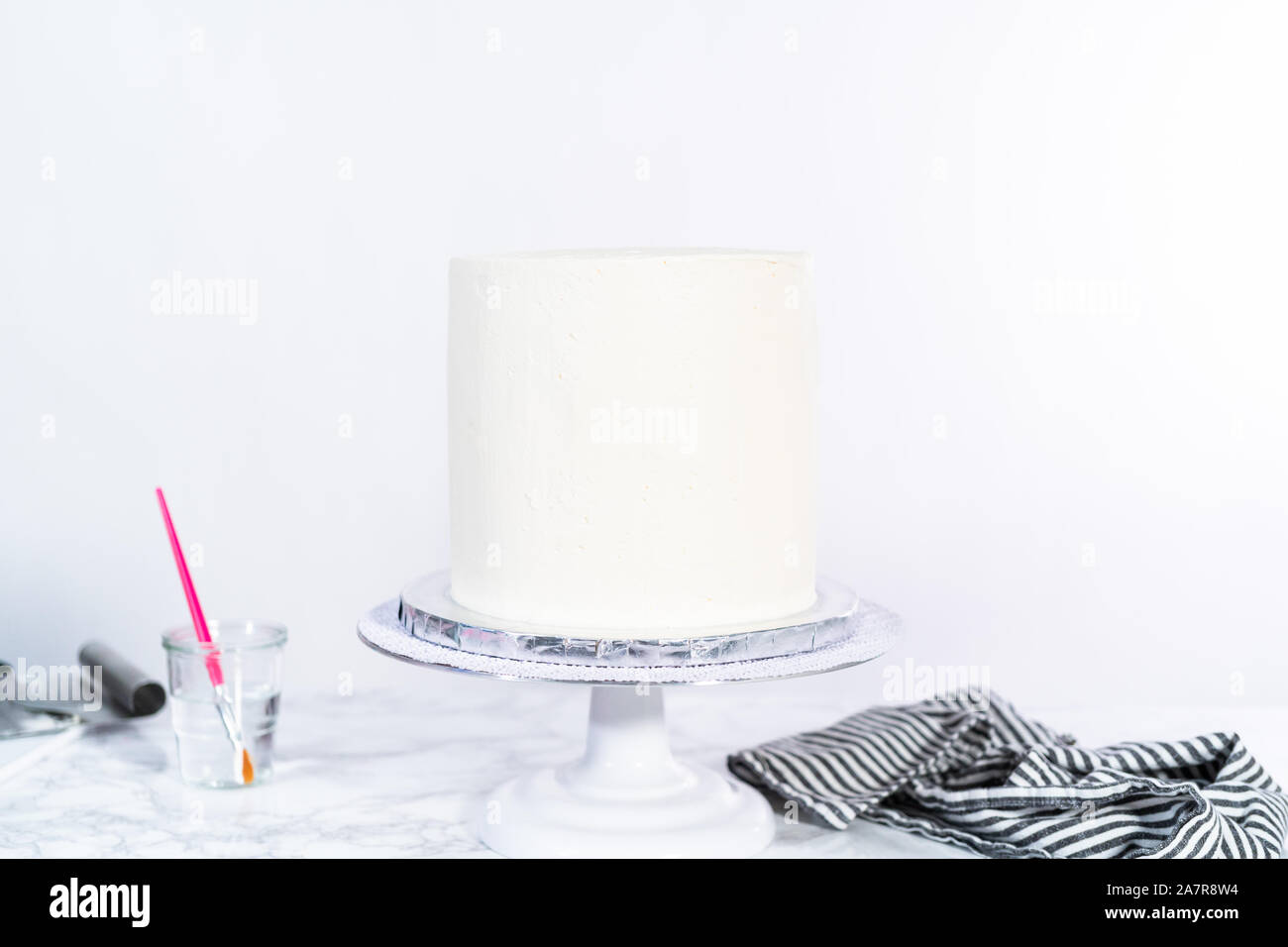 Frosting a tall round cake with white Italian buttercream icing Stock
