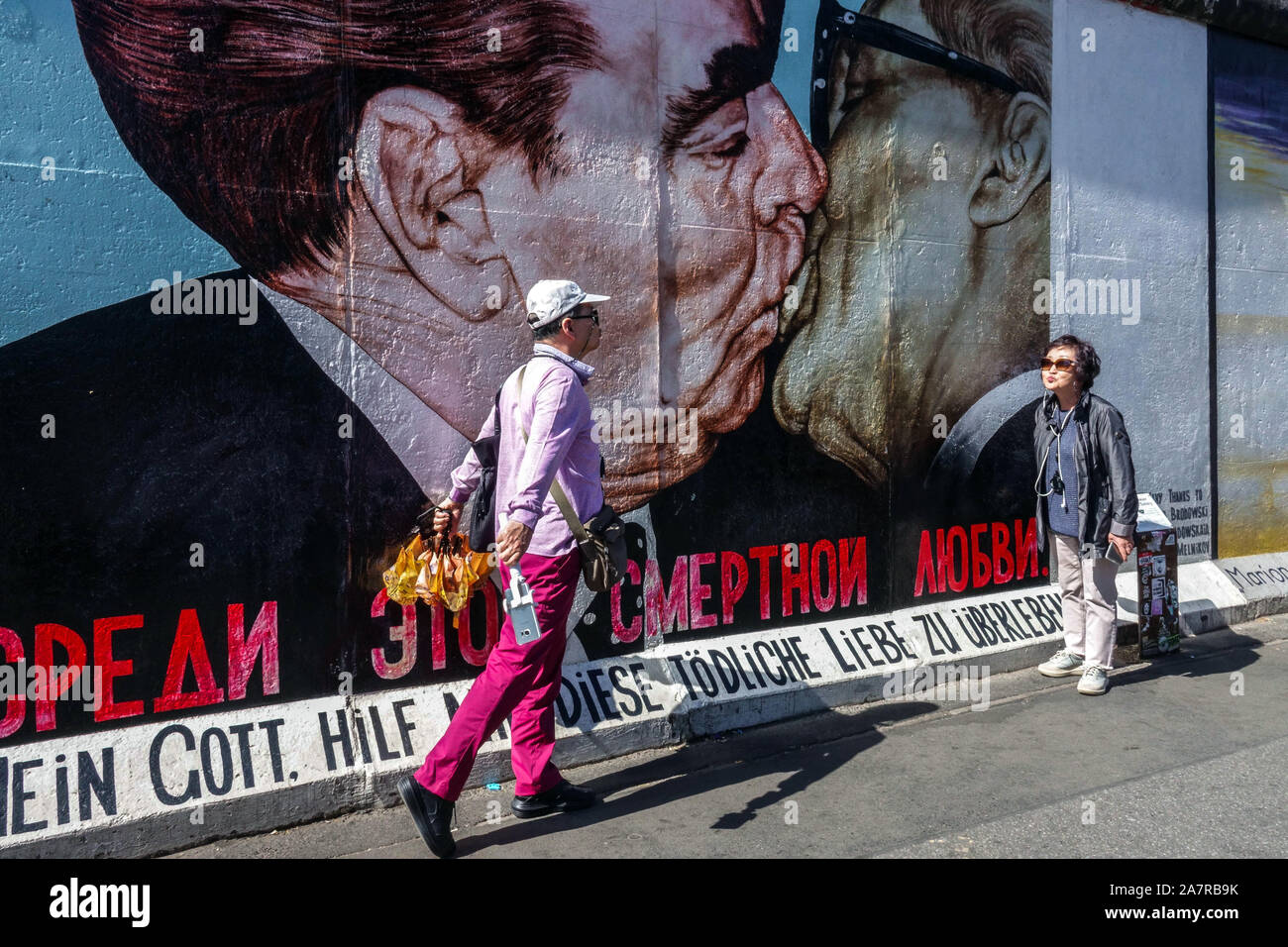 Berlin wall East Side Gallery, Asian tourists under frightening kiss Brezhnev Honecker Germany Europe Stock Photo