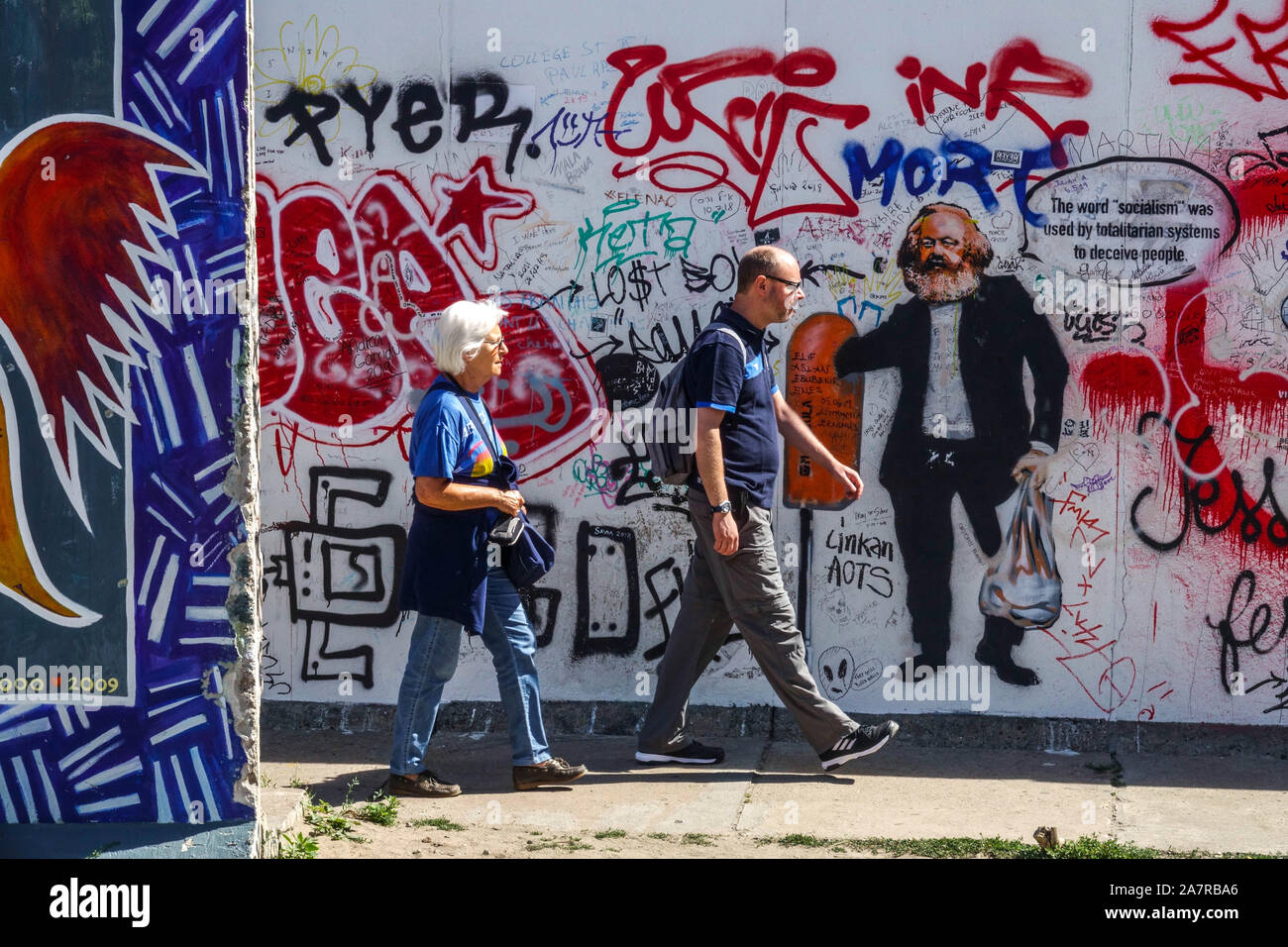Berlin wall graffiti tourists passing around Karl Marx Berlin East Side Gallery Germany Friedrichshain city street art Stock Photo