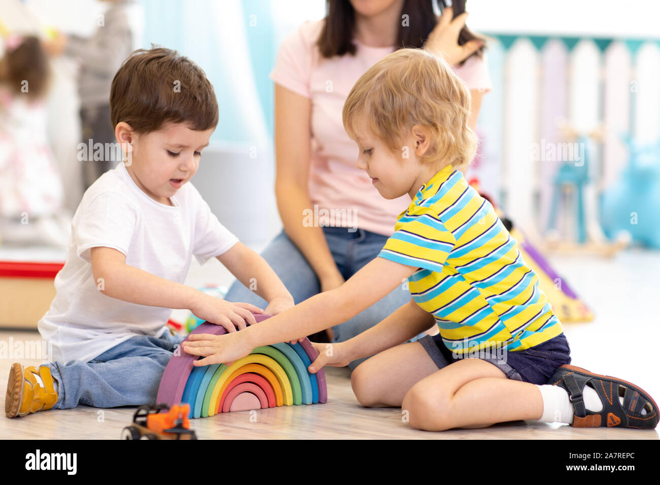 Preschool children playing with colorful wooden toys in kindergarten ...