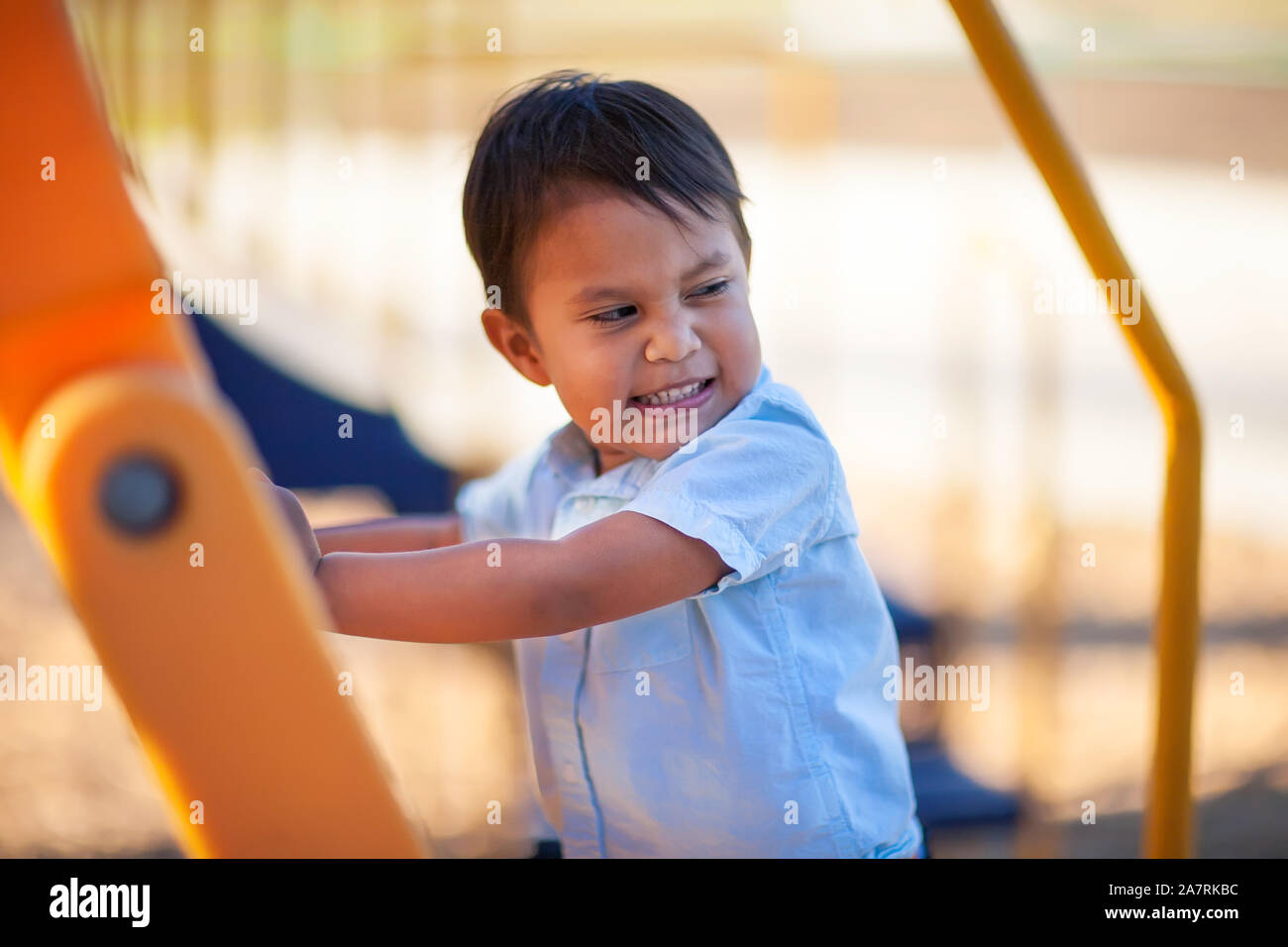 Young boy happy to climb up a playground ladder. Stock Photo