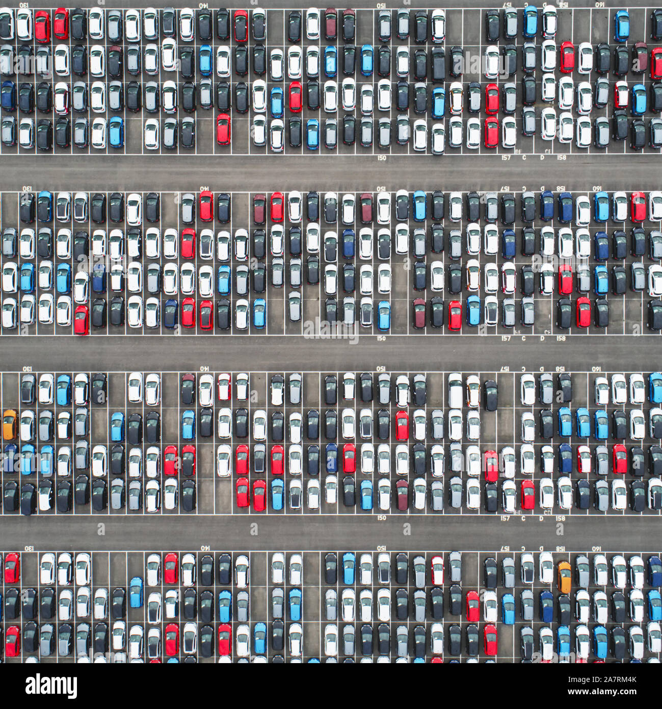Aerial view of an enormous parking lot filled with new imported cars