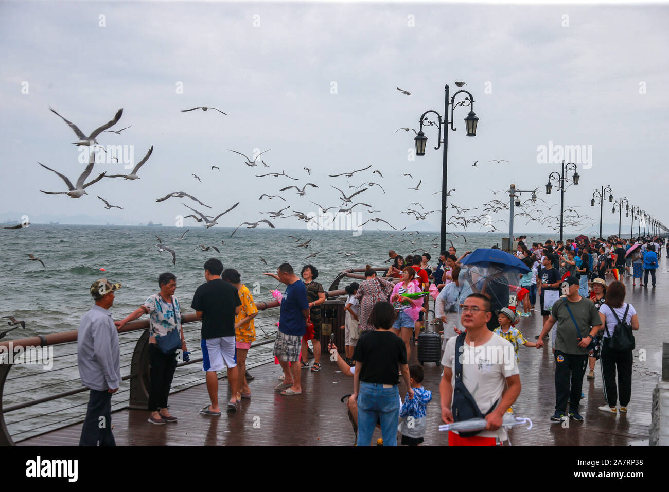 Citizens plays and take phots at seacoasts when several-meter-high waves appear as Lekima, the ninth Typoon of the year, in Dalian city, east China’s Stock Photo