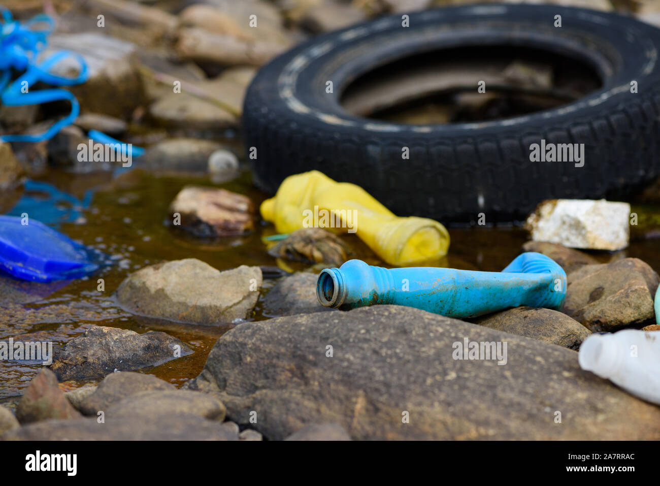 Enviroment pollution. Old tire bottles and plastic trash on ocean shore. Stock Photo