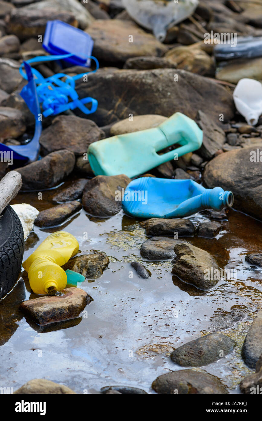 Plastic garbage and old tire in oily dirty water on ocean beach Stock Photo