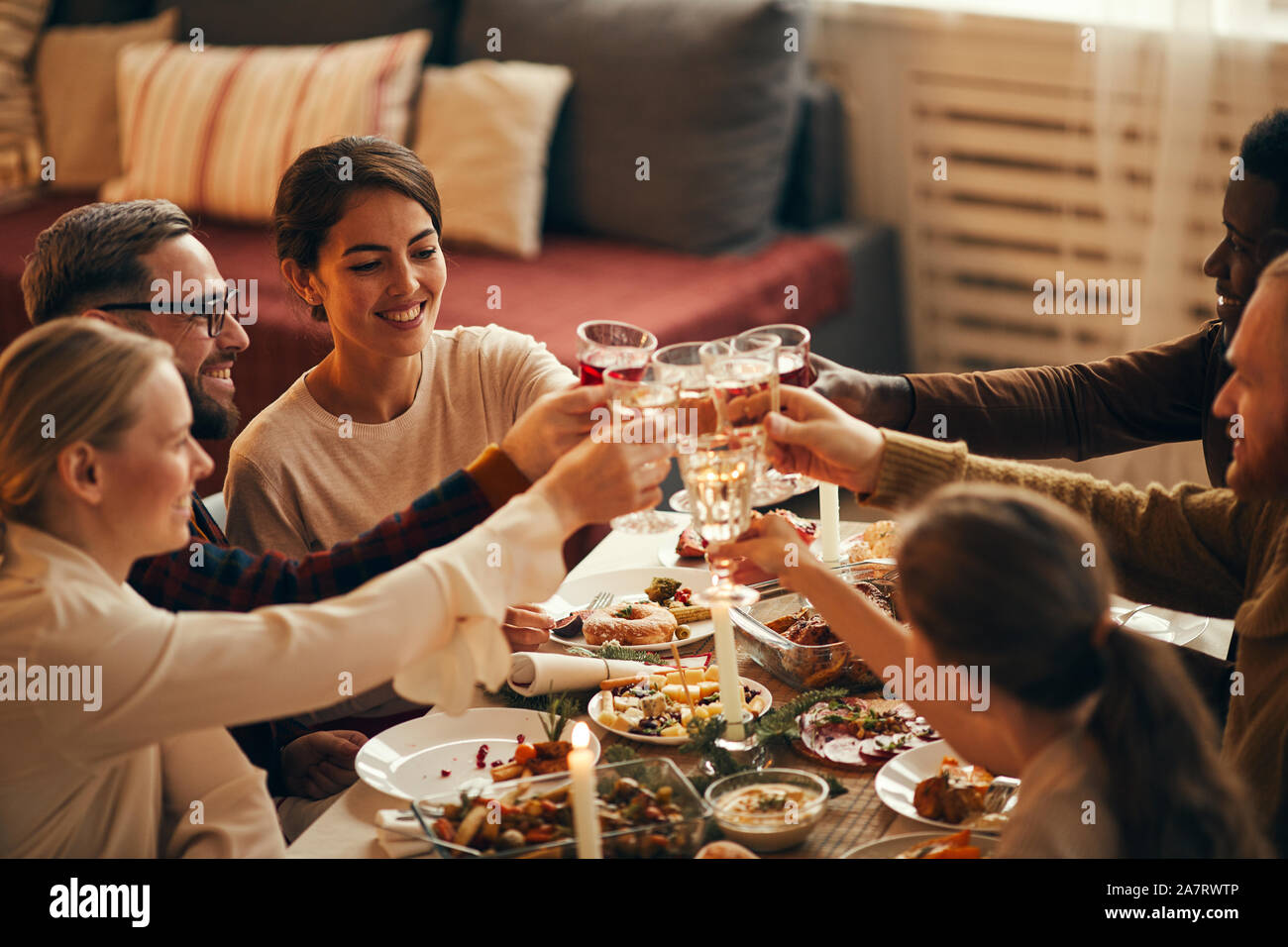 High angle view at elegant young people clinking champagne glasses while enjoying Christmas dinner at home, copy space Stock Photo