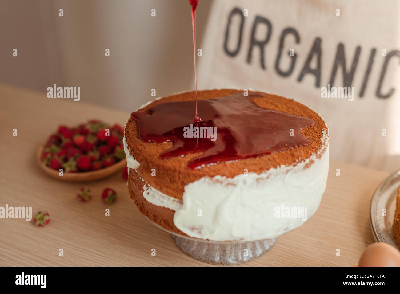 fresh sponge cake with raspberry syrup being poured over the top. Making red velvet or sponge cake process Stock Photo