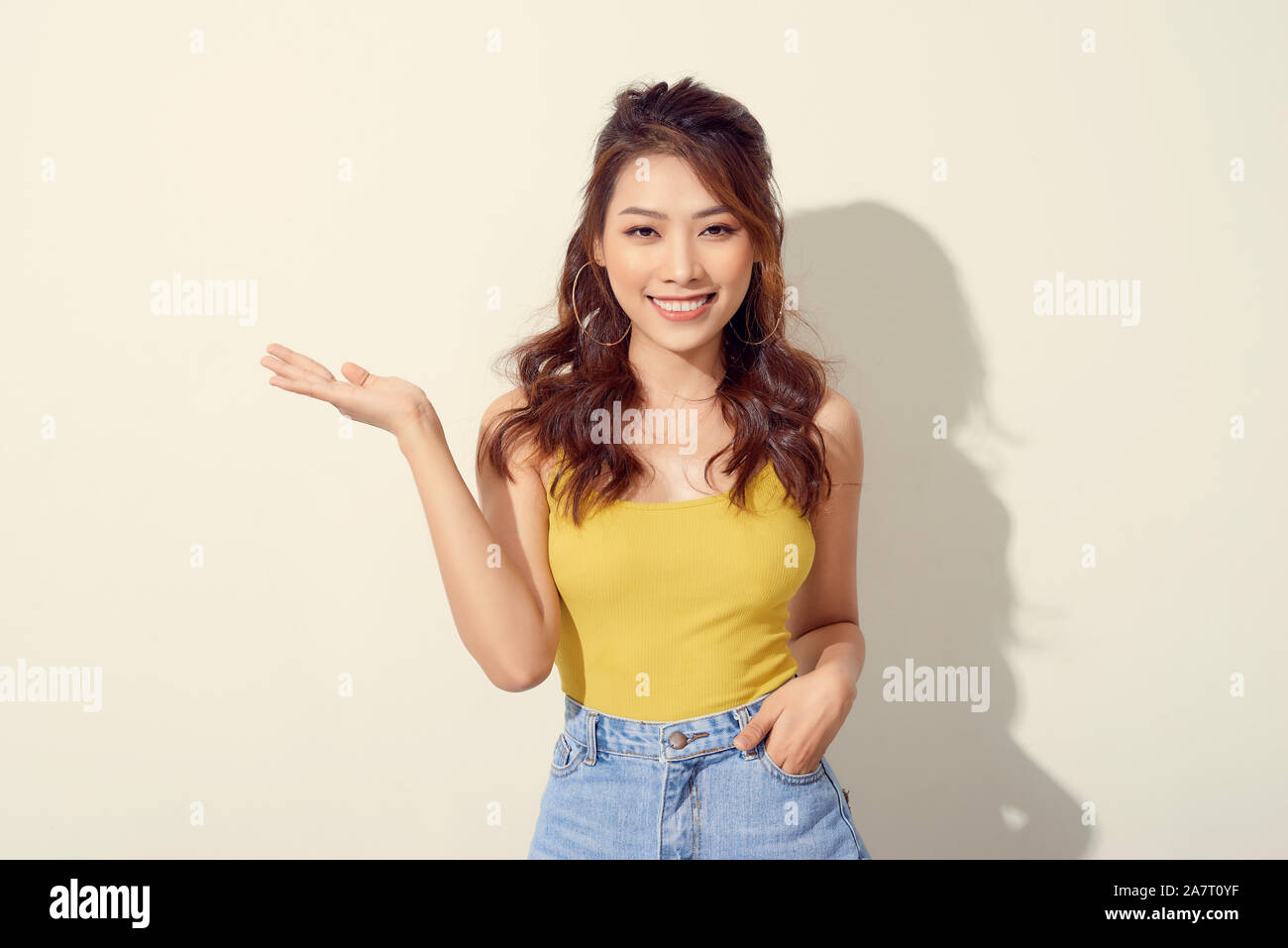 Smiling asian woman showing open hand palm to to the copy space for ...