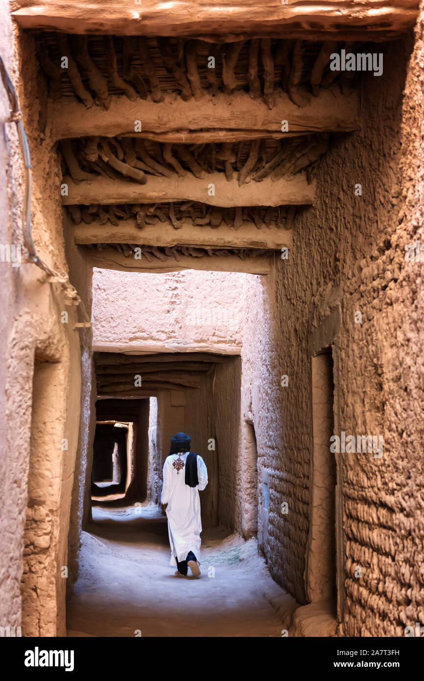 Traditional dressed man walks through an arch way inside a kasbah. Stock Photo