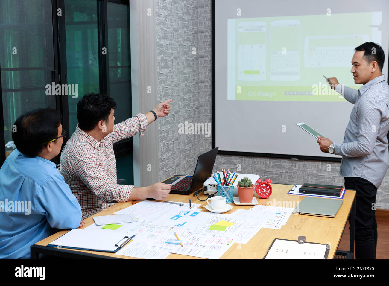 Graphic designers presenting UX UI designer planning application template layout framework for mobile phone computer mobile to developer team Stock Photo