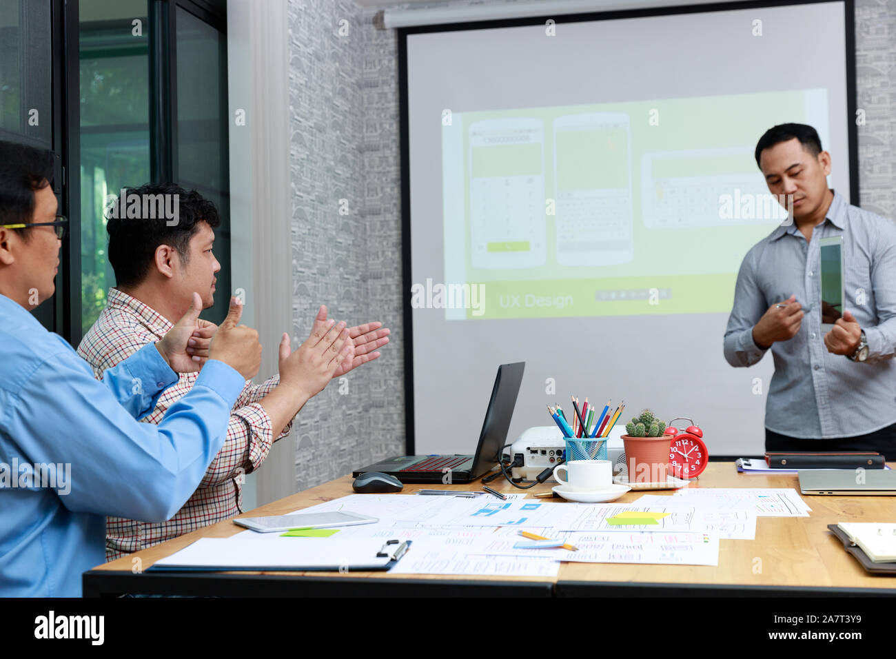 Graphic designers presenting UX UI designer planning application template layout framework for mobile phone computer mobile to developer team Stock Photo