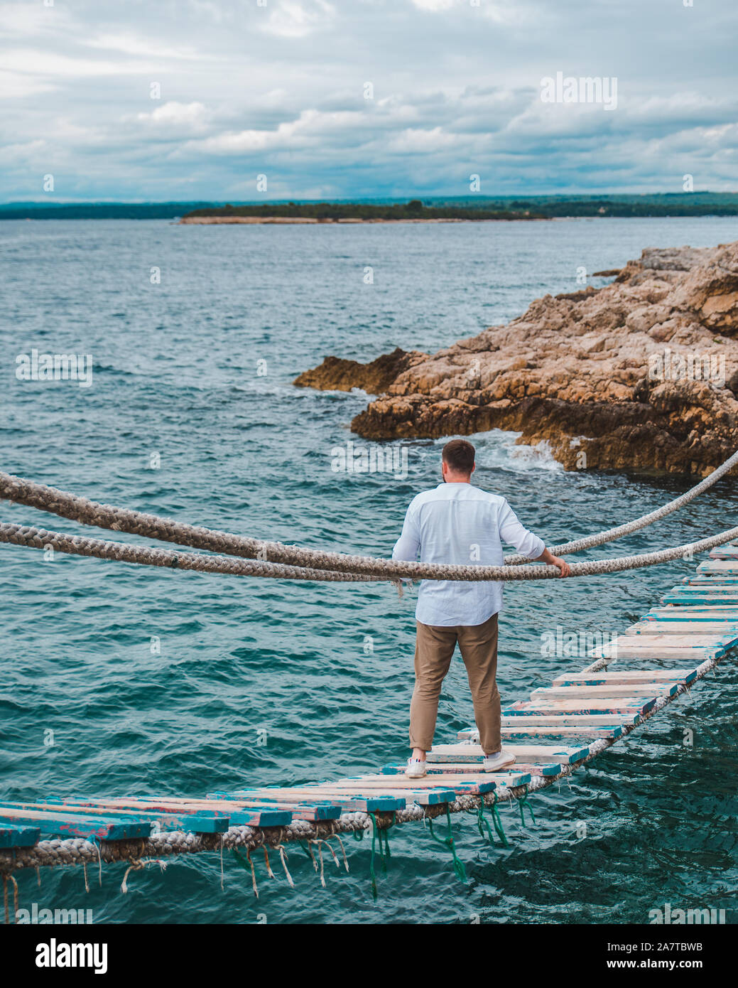 man walking by suspension bridge cross sea bay Stock Photo - Alamy