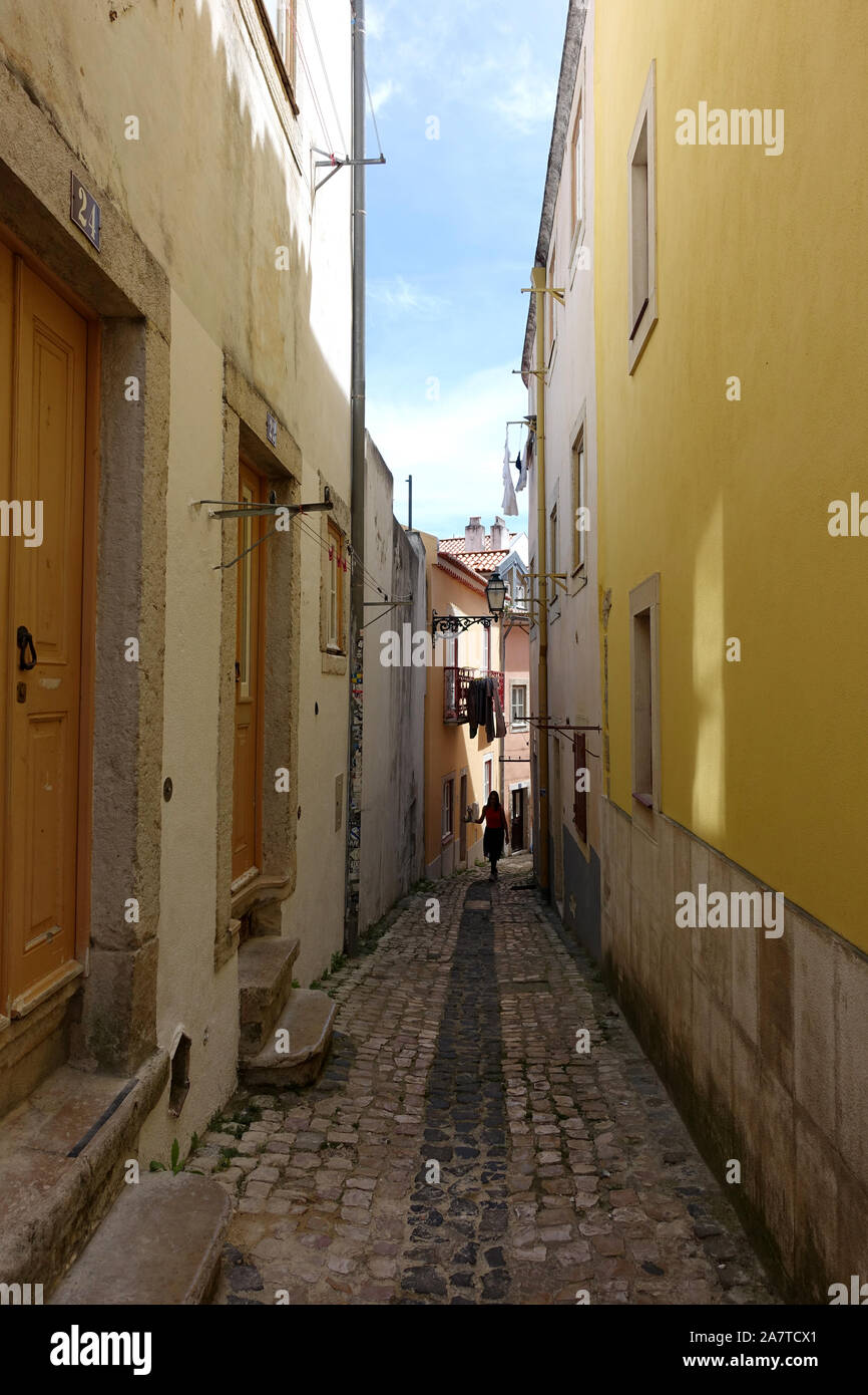 Lisbon, Portugal 16 April 2019: A tourist walking down a narrow alleyway in the old town of Lisbon, Portugal Stock Photo