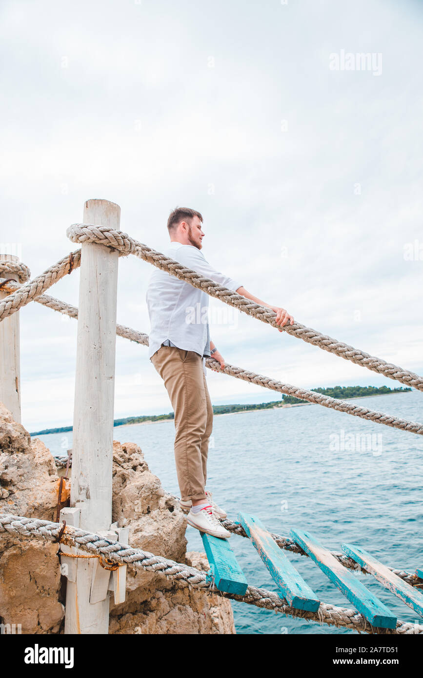 man walking by tourist suspension bridge crossing sea bay Stock Photo ...