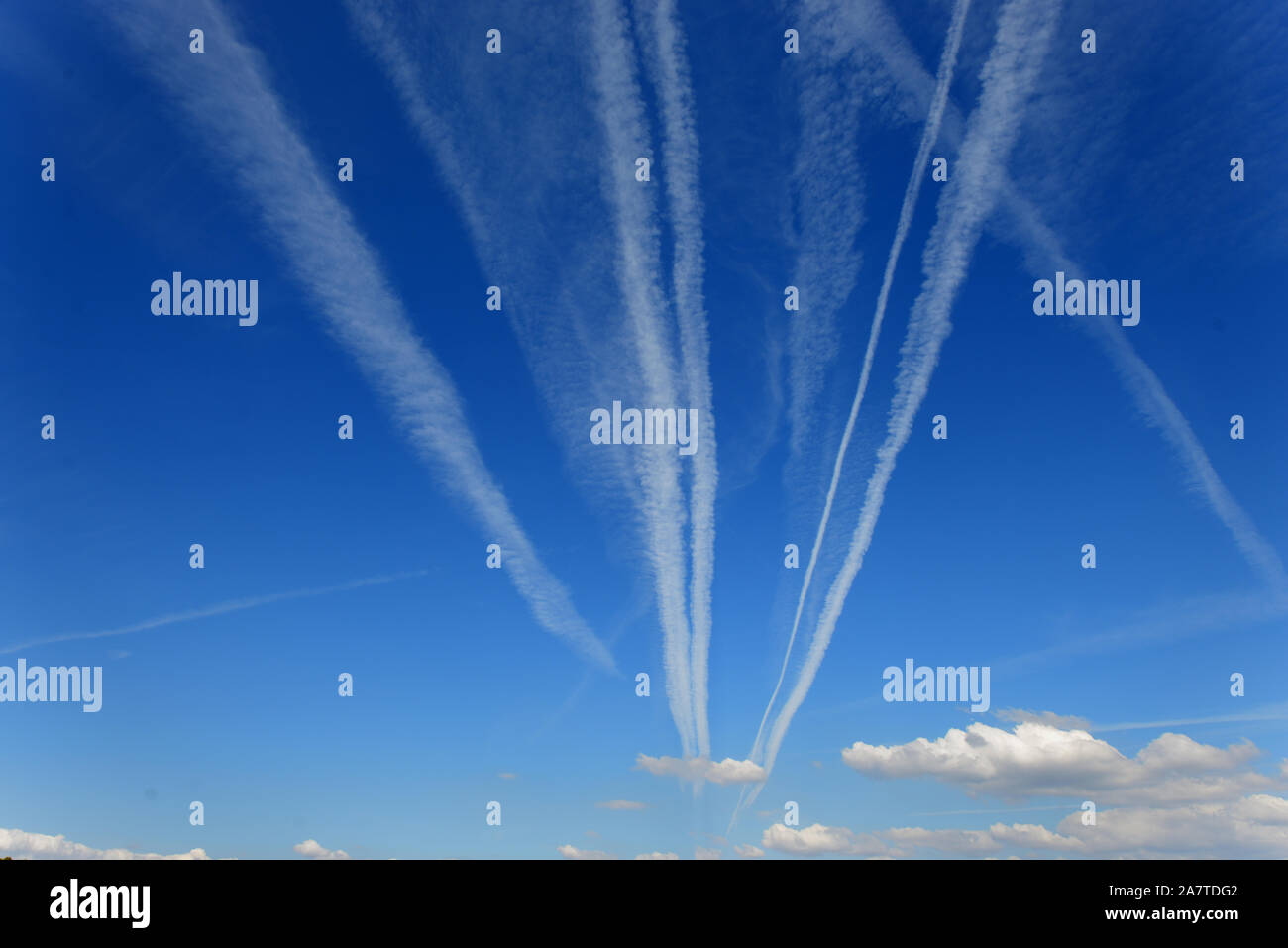 Vapour Trails, Contrails, Condensation Trails, Line-Shaped Clouds or Homogenitus Converging to Vanishing Point in Blue Sky Stock Photo