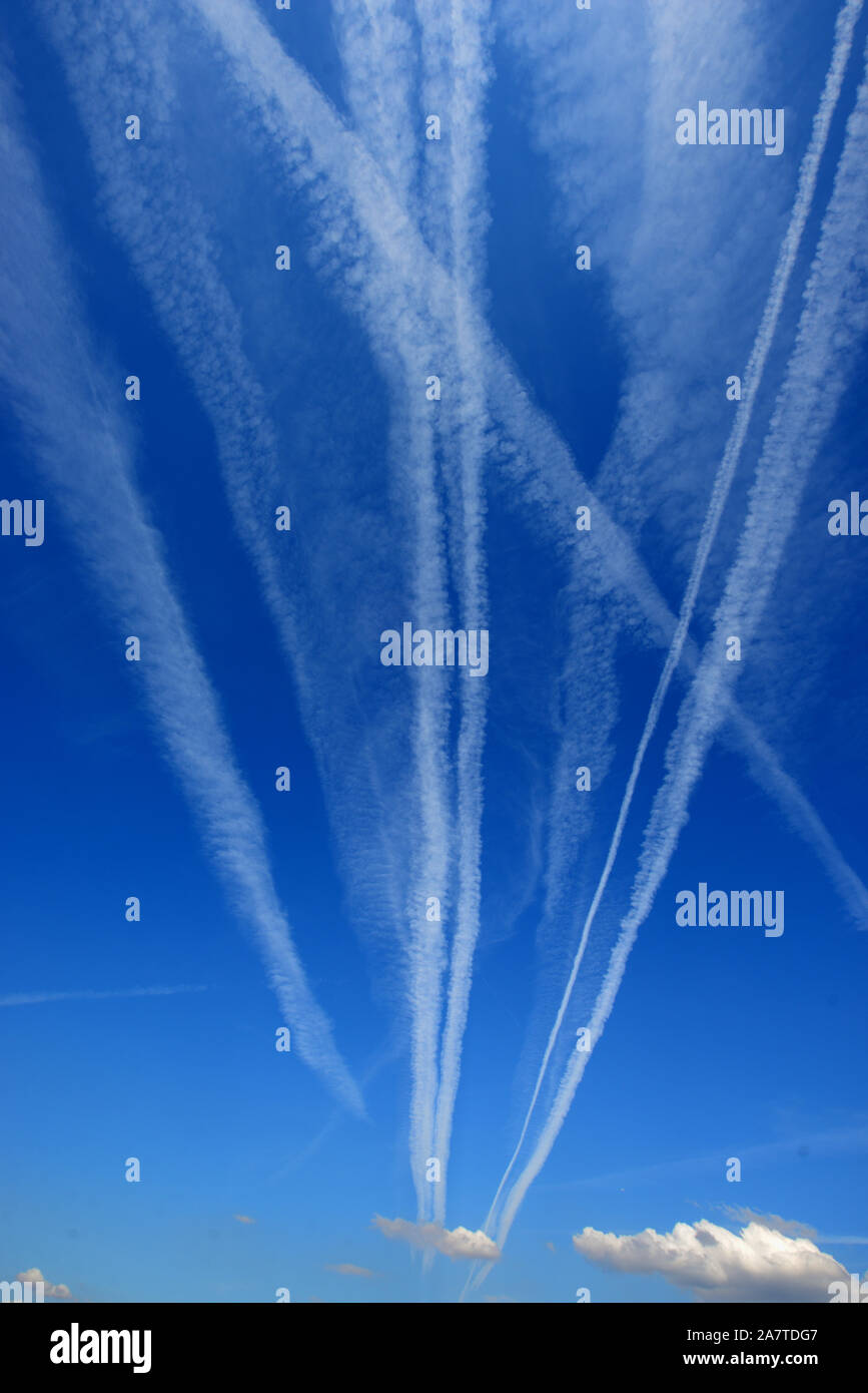 Vapour Trails, Contrails, Condensation Trails, Line-Shaped Clouds or Homogenitus Converging to Vanishing Point in Blue Sky Stock Photo