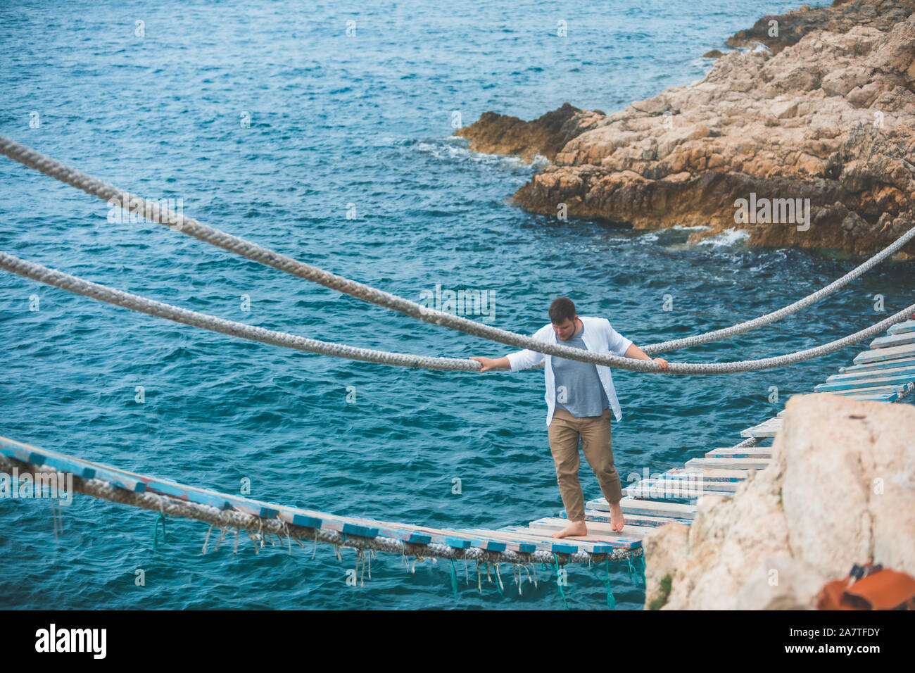 man walking by suspension bridge cross sea bay Stock Photo - Alamy