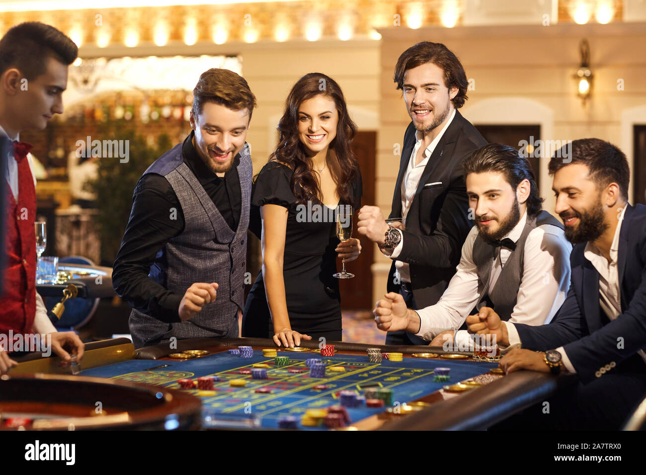 Friends make bets gambiling at the roulette table in the casino. Stock Photo