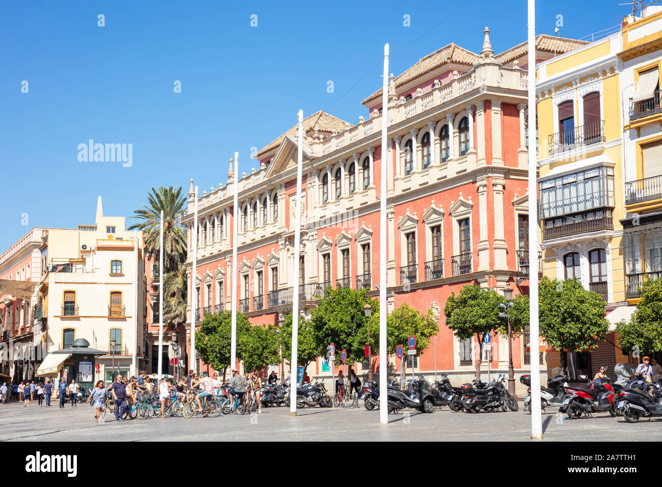 Cyclists on a city cycle tour gathering outside buildings with typical spanish architecture in the Plaza de San Francisco Seville Spain EU Europe Stock Photo