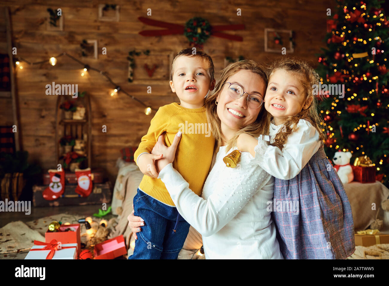 Happy mom hugs children in a room at Christmas Stock Photo