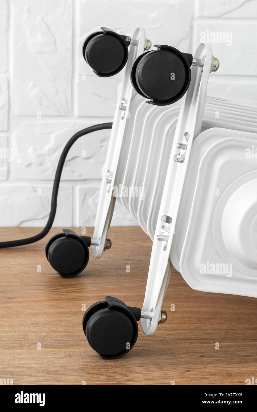 Four plastic twin wheels just installed on an electric oil heater. White oil-filled  radiator with four black wheels. Home heating and comfort Stock Photo -  Alamy