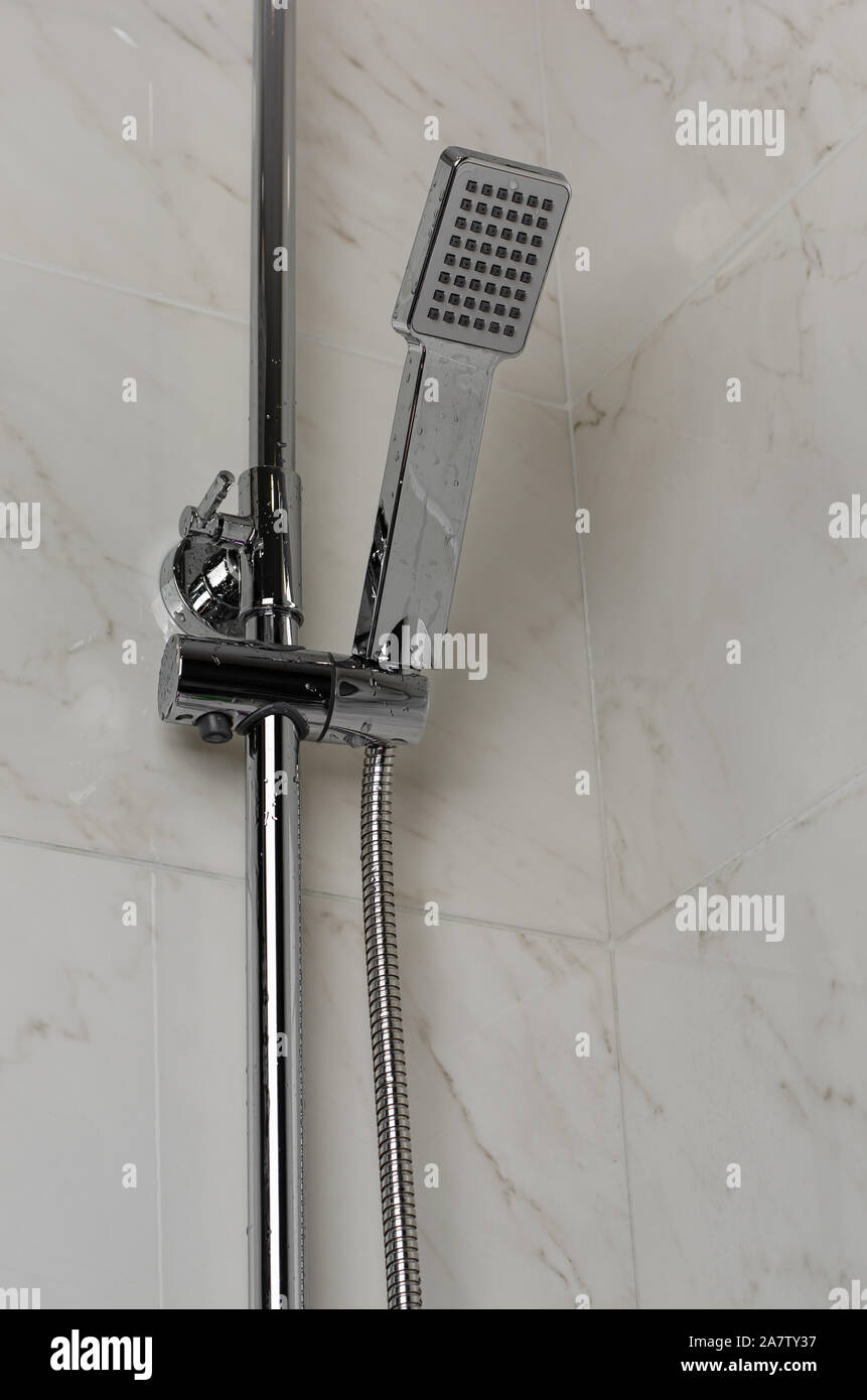 Wet shower head hanging on the wall Stock Photo
