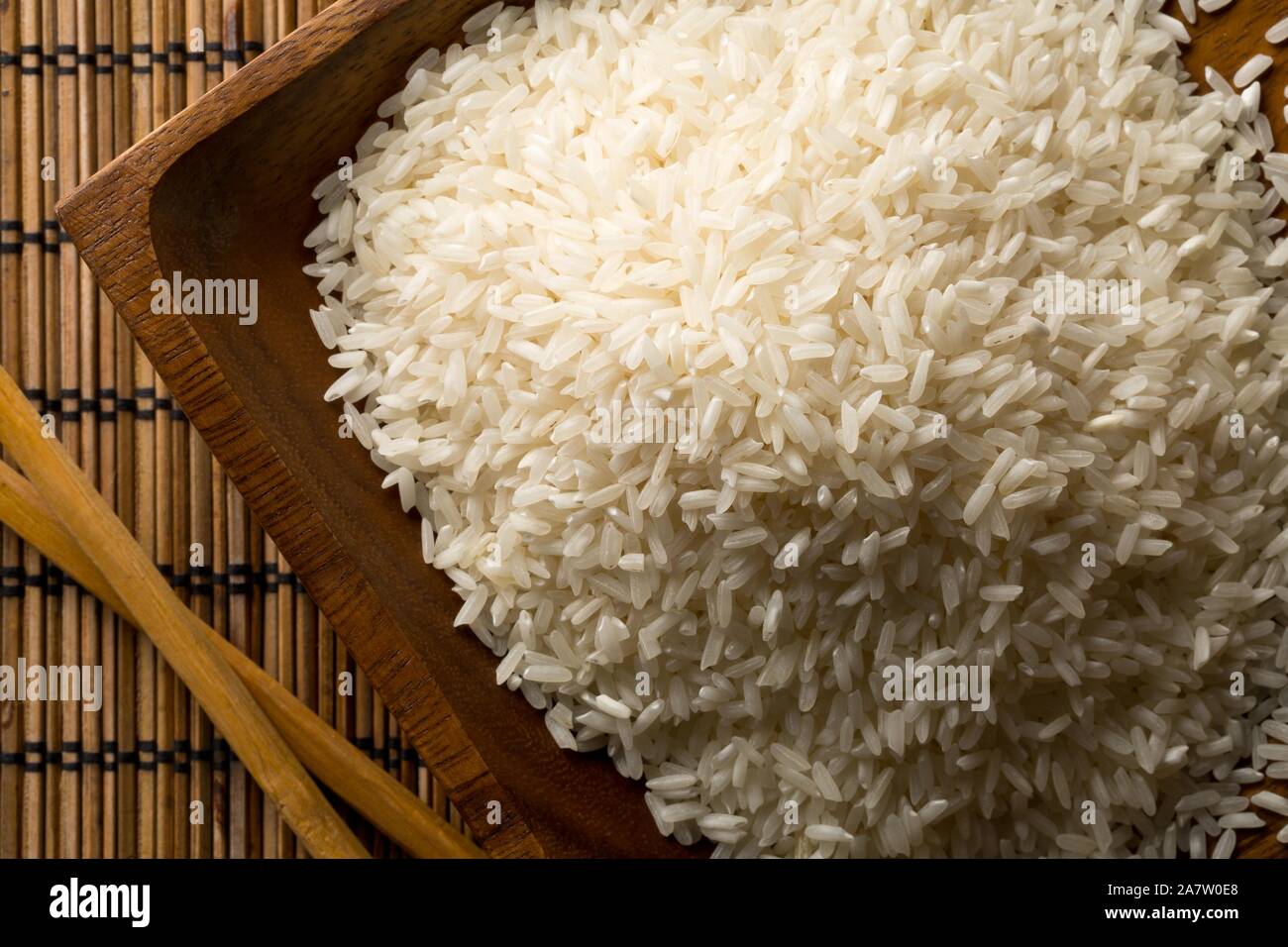 Rice Without Shell White uncooked, raw long grain rice in wooden bowl with chopsticks on ...