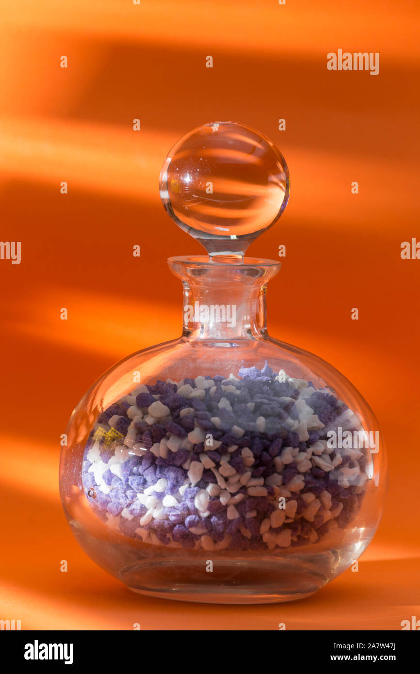 glass jar with ball cap, full of colored pebbles, centered on an orange