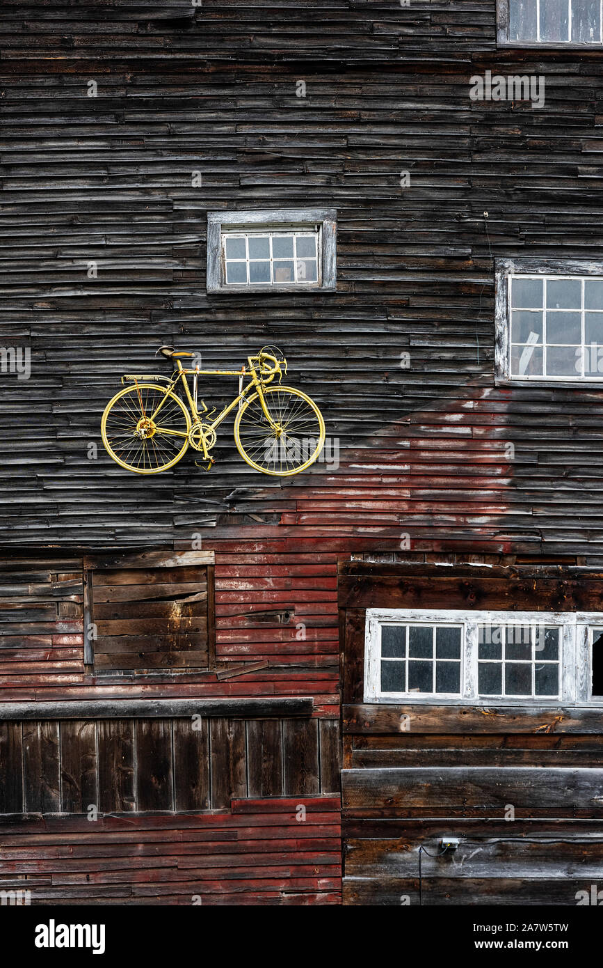 Yellow bike displayed on a barn  exterior facade, Vermont, USA. Stock Photo
