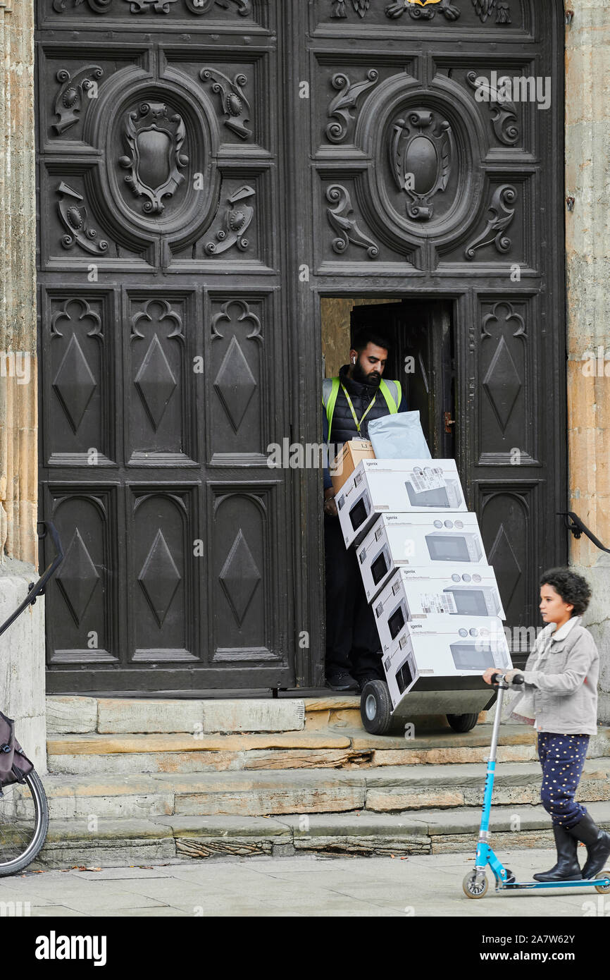 A man makes a delivery through the entrance door to University college, university of Oxford, England. Stock Photo
