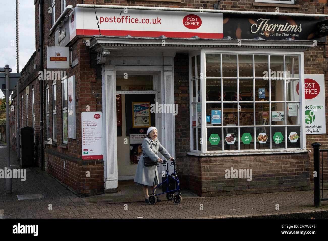 Elderly lady supported by a Tri Wheel Walker outside Gerrards Cross post office, Buckinghamshire, England, United Kingdom Stock Photo