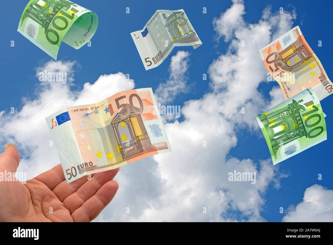 Open hand and flying banknotes on the sky Stock Photo