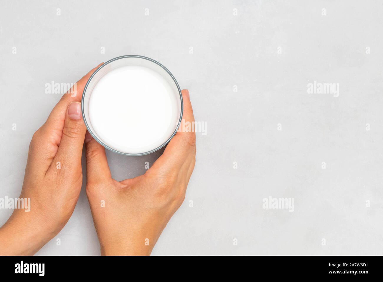 Woman hands holding a glass of ayran (kefir) fermented drink on grey concrete background Stock Photo