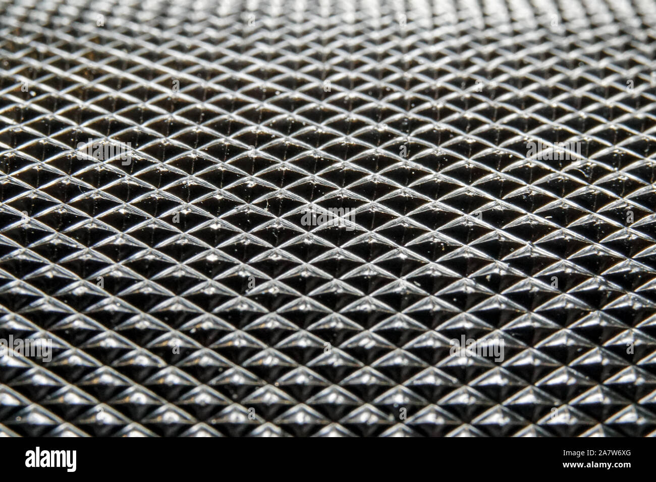 Abstract macro close-up of industrial black color circular metal part with dense pyramid pattern relief in partial focus Stock Photo