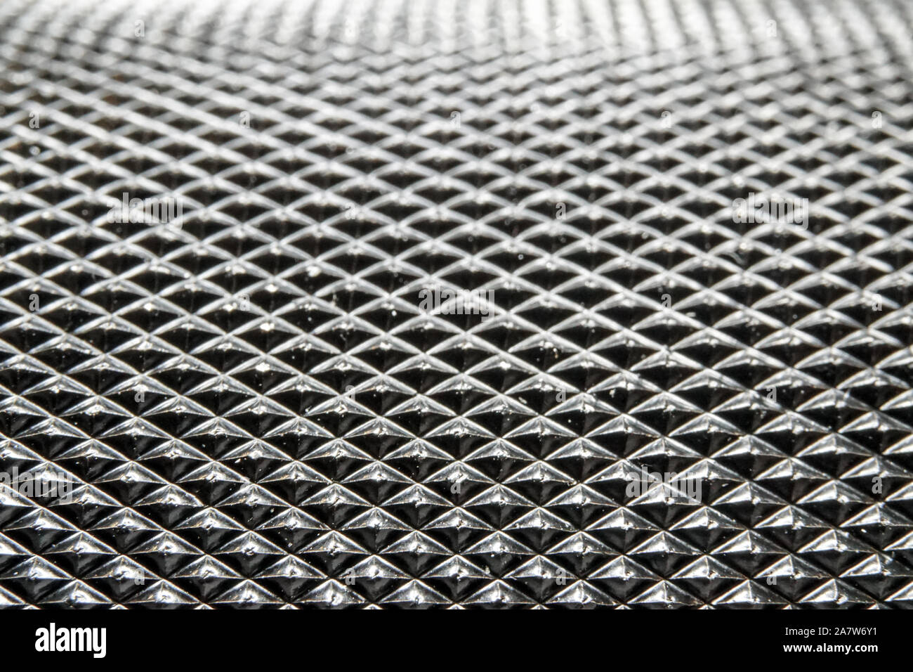 Abstract macro close-up of industrial black color circular metal part with dense pyramid pattern relief in partial focus Stock Photo