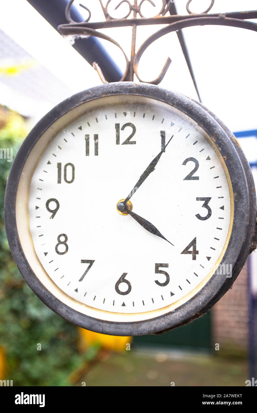 Antique vintage style clock hanging outside, hanging on the wall of a